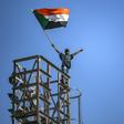 A protester waves a Sudanese flag on top of a tower during a sit-in outside the army headquarters in the capital Khartoum on April 30, 2019