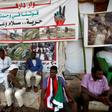 Sudanese men displaced from Darfur sit next to a tent outside the military headquarters in the capital Khartoum at the ongoing sit-in