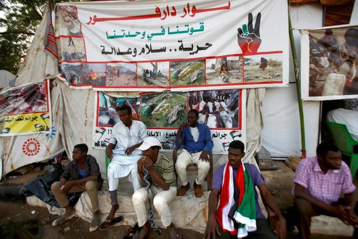 Sudanese men displaced from Darfur sit next to a tent outside the military headquarters in the capital Khartoum at the ongoing sit-in