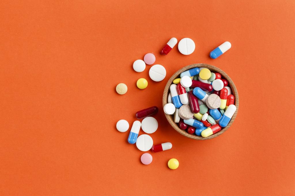 Multi-colored pills scattered on a bright background, a place for text.