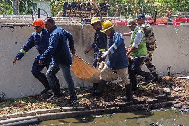 Firefighters carry a victim’s body after the Air India flight 171 crashed in a residential area near the airport in Ahmedabad on June 12, 2025. (Photo by Sam PANTHAKY / AFP)