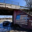 A car drives past graffiti reading "Thank You NATO" and featuring the US flag near the village of Stagovo, Kosovo on March 24, 2019, 20 years after the start of the alliance's bombing campaign