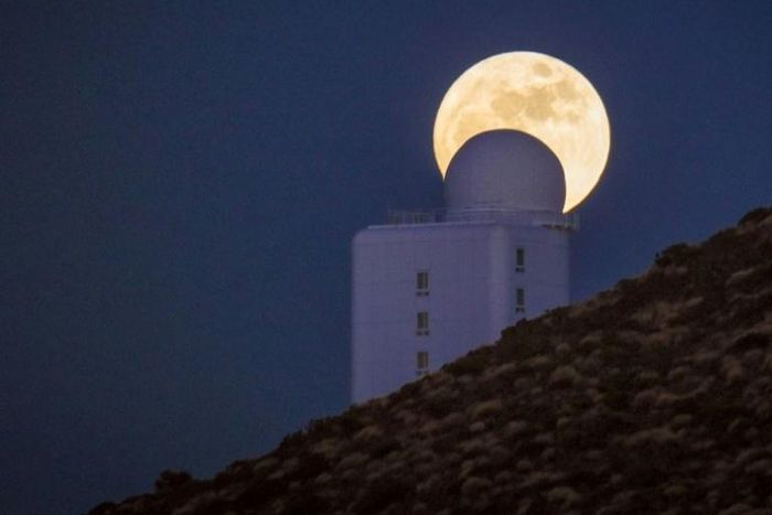 (FILES) In this file photo taken on December 13, 2016 the full moon is seen behind a telescope of the Spain's Institute of Astrophysics of the Canary Islands, in the National Park of El Teide, on the Spanish canary island of Tenerife on December. A tea...