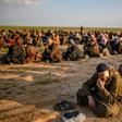 Suspected Islamic State fighters wait to be searched by members of the Kurdish-led Syrian Democratic Forces