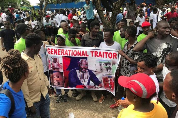 Demonstrators hold a poster portraying Liberian President George Weah as they gather outside the Liberian Mansion in Monrovia on June 7, 2019 during an anti-government march to protest inflation and corruption