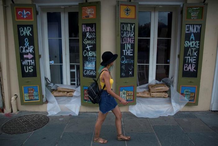 A woman walks past a cigar lounge and bar protected by sand bags in the French Quarter of New Orleans, in preparation for tropical storm Barry