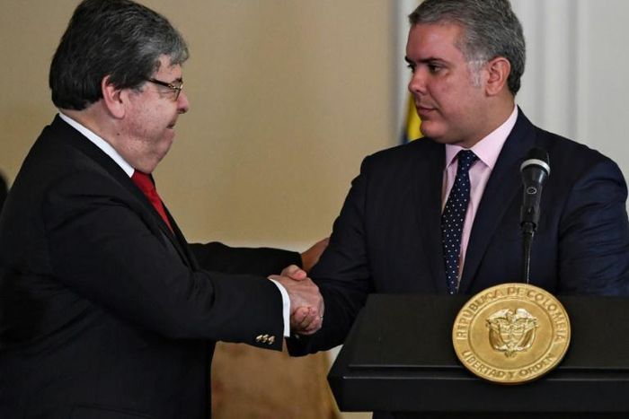 Colombian President Ivan Duque (R) shakes hands with Colombian Foreign Minister Carlos Holmes Trujillo during the signing of a decree that allows the nationalization of 24,000 children of Venezuelan parents born in Colombia August 5, 2019