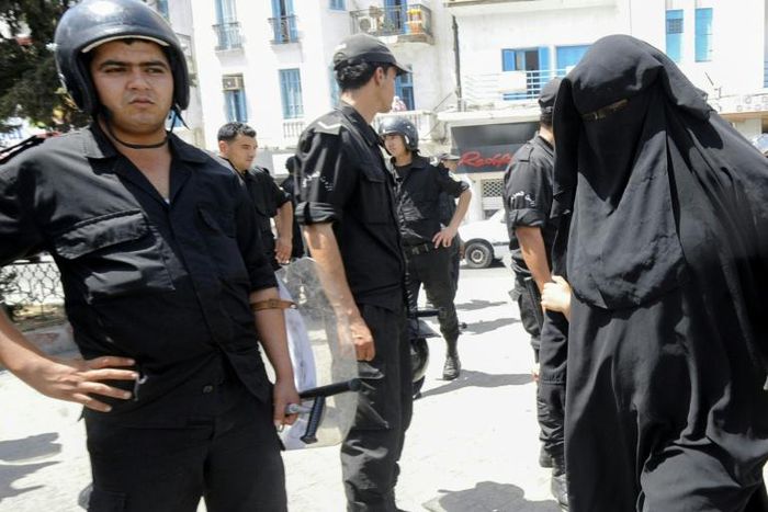 In this file photo from June 2012, a Tunisian woman, wearing a niqab, walks in front of police officers after Friday prayers
