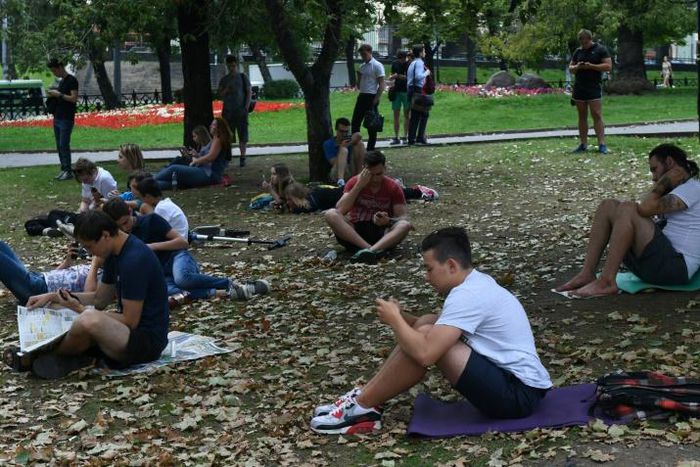 People look at their smartphones in central Moscow in August 2016 -- dating app Tinder has now been required to register with Russian security services