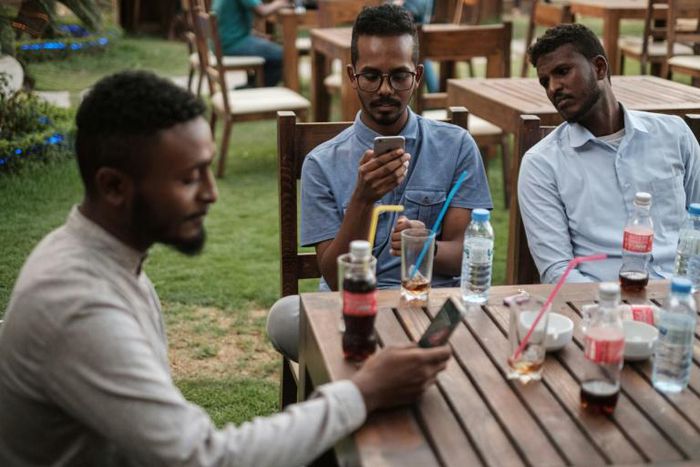 Mohamed Omar (L) sits with his friends at a cafe in an upscale district of Sudan's capital on June 17, 2019