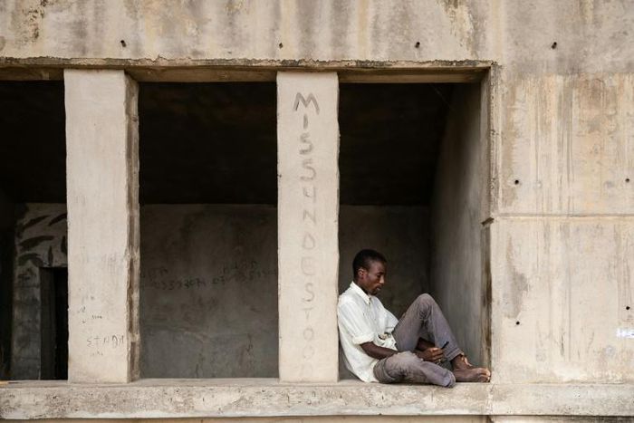 A man pages through his mobile phone while sitting at the Mohammed Goni Stadium internally displaced camp in Maiduguri, northeast Nigeria on July 26, 2019. Sixty-five people were killed and more wounded when Boko Haram fighters raided a camp for people...