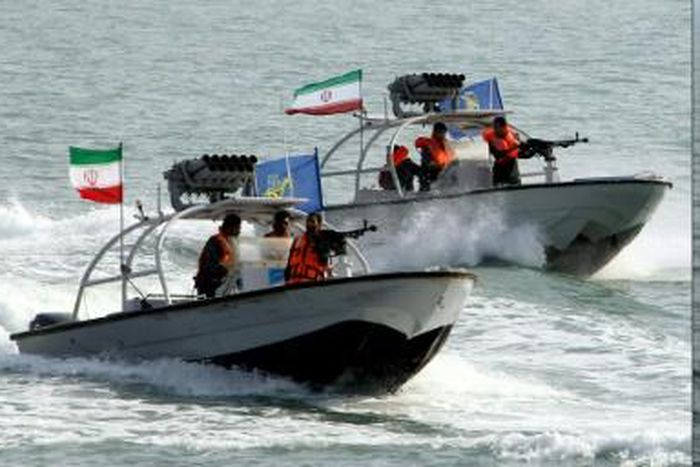 Iranian Revolutionary Guards drive speedboats at the port of Bandar Abbas in 2012 (L), and the amphibious assault ship USS Boxer is pictured during exercises in 2016