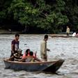 Venezuelans take boats from one muddy shore to the other to buy supplies from Colombia or journey onwards