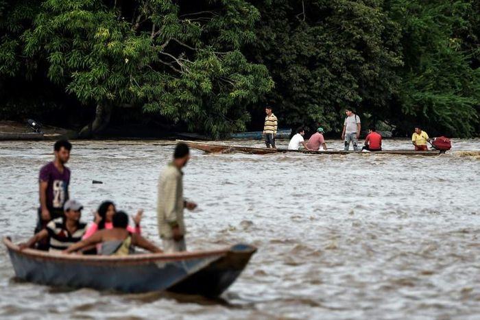 Venezuelans take boats from one muddy shore to the other to buy supplies from Colombia or journey onwards