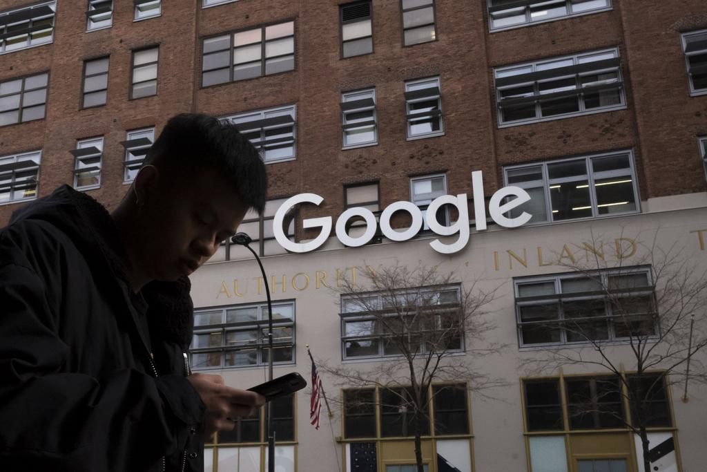 FILE - In this Dec. 17, 2018, file photo, a man using a mobile phone walks past Google offices in New York. Executives from Google and Facebook are facing Congress Tuesday, April 8, 2019, to answer questions about their role in the hate crimes and the ...