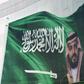 Saudi King Salman and his son Crown Prince Mohammed appear next to a Saudi flag on a billboard in Riyadh