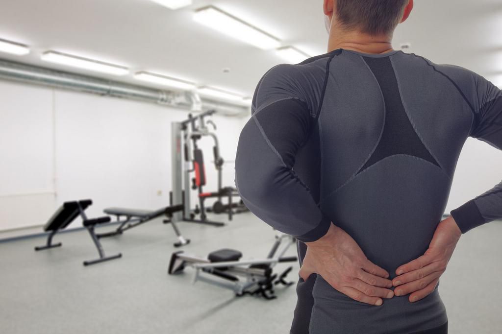 Man with low back pain in gym. Sports exercising injury