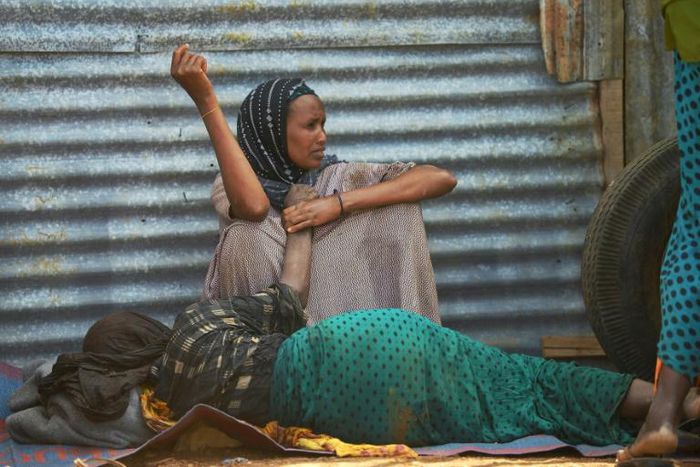 An elderly woman weakened by hunger lies on the ground as her daughter watches over her at a camp for the internally displaced on the outskirts of Baidoa town, the capital of Bay region of south-western Somalia