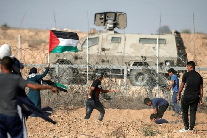 Palestinian demonstrators throw stones at Israeli security forces during protests along the border with Israel east of Khan Yunis, in the southern Gaza Strip