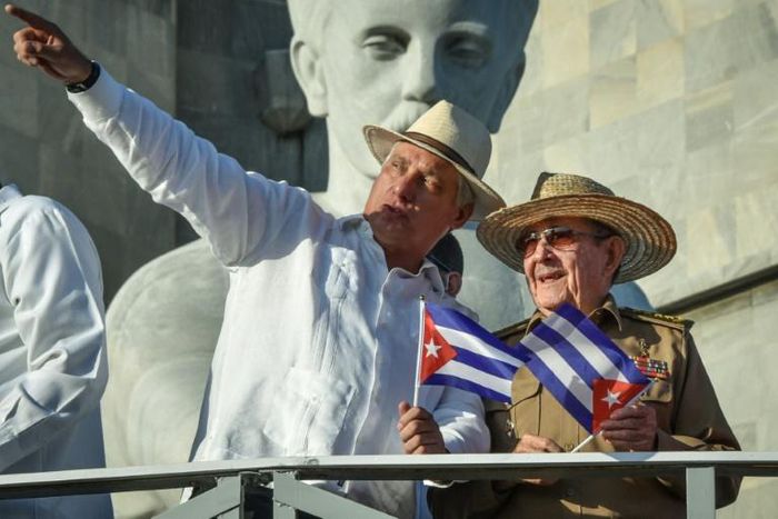 Cuban President Miguel Diaz-Canel (with his arm raised) stands next to Raul Castro, first secretary of the island's Communist Party, on May 1, 2019 in Havana; a new law will bring governmental change without touching the central role of the party