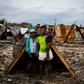 Iris Daniel, 57, Lovely Saint-Pierre, 32, and Evanston Daniel, 5, pose on May 25, 2019, outside a makeshift shelter on the site of their home which was burned during a November 2018 gang war in Port-au-Prince