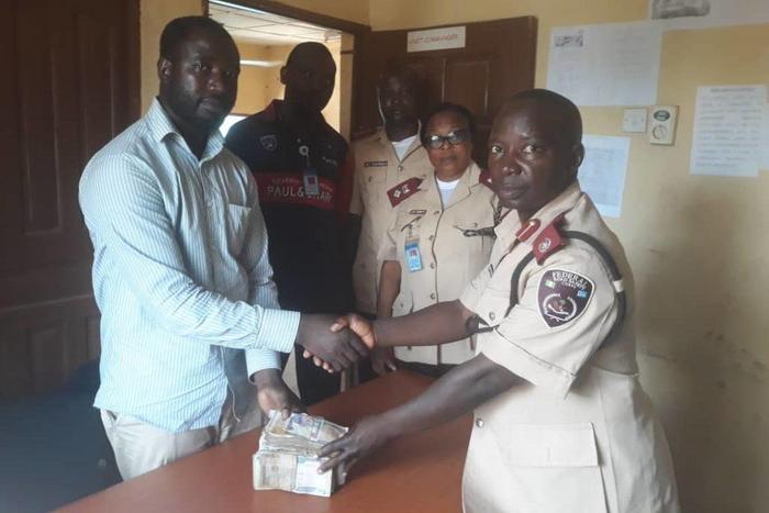 The Unit Commander presenting the cash to the victim’s relation (NAN)