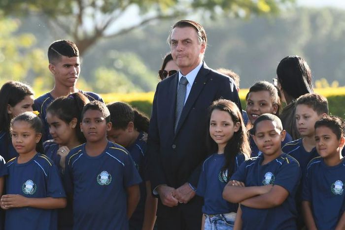 Brazilian President Jair Bolsonaro, seen during a May 21, 2019 event with a school group in Brasilia, has defended the practice of child labor though it is banned in his country