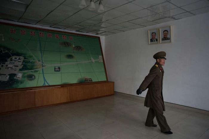 A Korean People's Army soldier walks past a map of the joint security area and Demilitarized Zone (DMZ) separating North and South Korea, in Panmunjom