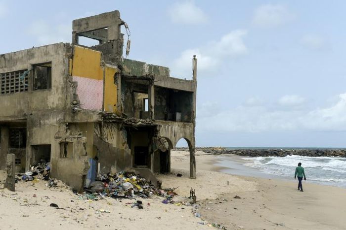 The shore-hugging Alpha Beach road has disappeared under the waves and apartment blocks built with prized ocean views just 10 years ago are now occupied only by squatters