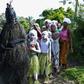 Young girls in white face paint take part in a procession to start their initiation into the Bondo secret society, alongside a figure called the Black Devil