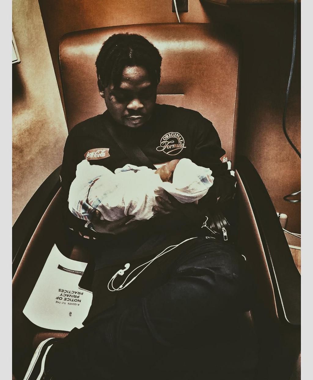 Olamide rocking his second son, Myles Adedeji [ Instagram/Baddosneh]