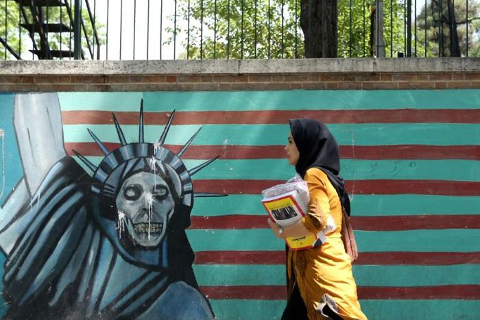 A woman walks past a mural on the wall of the former US embassy in the Iranian capital Tehran