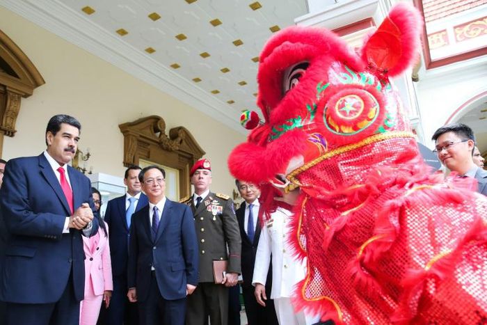 Venezuela's President Nicolas Maduro (L) and China's ambassador to Venezuela Li Baorong (C) watch a performance of a Chinese lion during a celebration marking 45 years of ties between the two countries, in June 2019
