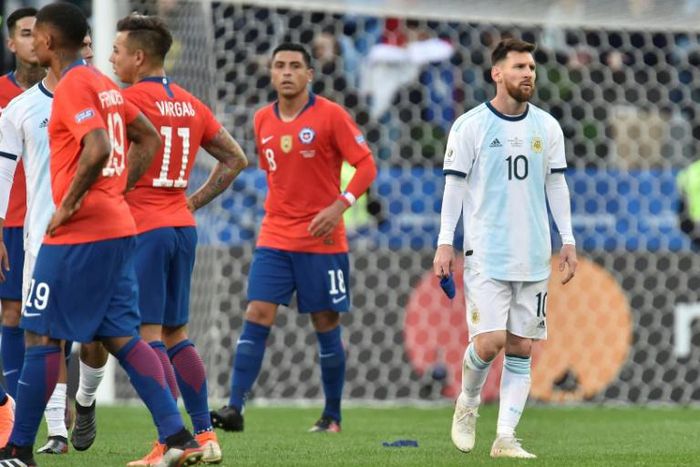 A dejected Lionel Messi (right) leaves the field after he and Chile's Gary Medel were sent off during the Copa America third-place match