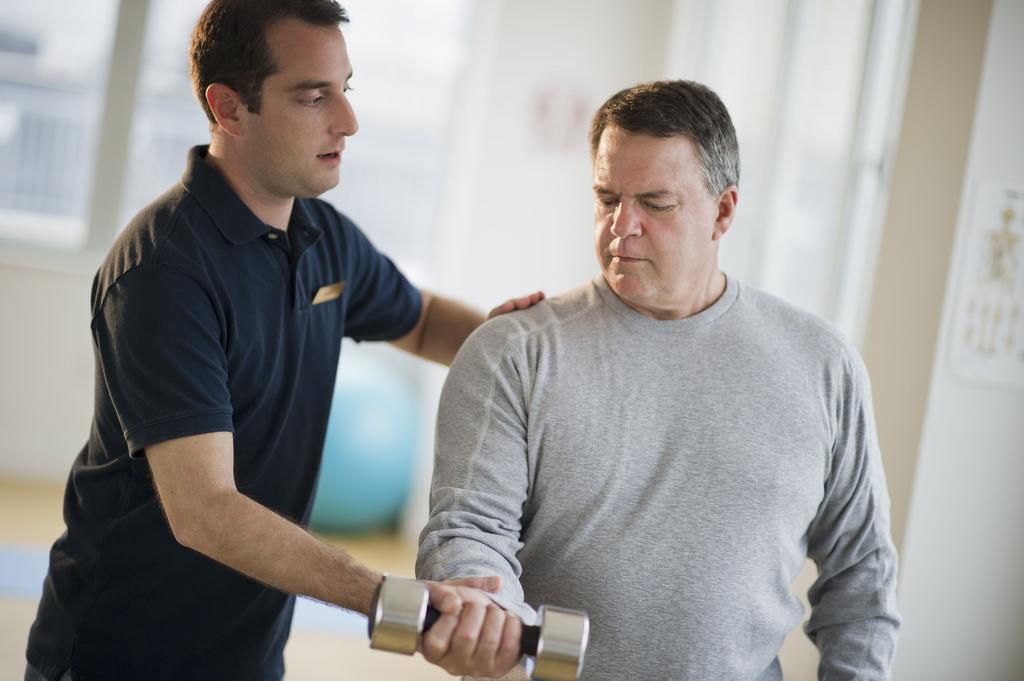 USA, New Jersey, Jersey City, Fitness instructor assisting man using hand weight in gym