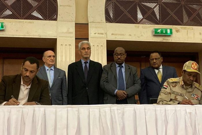 The deputy chief of Sudan's ruling miliary council Mohamed Hamdan Dagalo (R) and protest leader Ahmed al-Rabie (L) initial an agreement before AU and Ethiopian mediators in Khartoum early on Wednesday