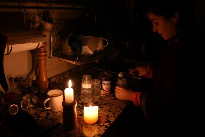 A woman prepares milk bottles by candle lights at her home in Montevideo during a massive power failure