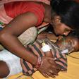 An Indian child suffering from Acute Encephalitis Syndrome is comforted at the Sri Krishna Medical College and Hospital in Bihar. Over 100 children have died of the lychee-linked virus this month alone