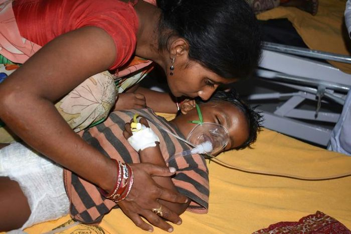 An Indian child suffering from Acute Encephalitis Syndrome is comforted at the Sri Krishna Medical College and Hospital in Bihar. Over 100 children have died of the lychee-linked virus this month alone