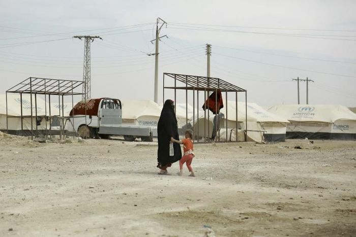A woman and child walk through the Al-Hawl refugee camp in northeast Syria, where families with Australia-based relatives are being held