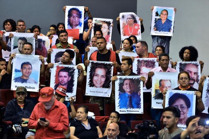 Relatives and friends of victims of the 2009 coup that ousted former president Manuel Zelaya hold portraits of their loved ones during a forum in Tegucigalpa on June 27, 2019