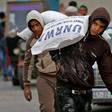 Palestinian men transport bags of flour outside an aid distribution centre run by the United Nations Relief and Works Agency (UNRWA), in Rafah in the southern Gaza Strip, in December 2018