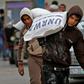 Palestinian men transport bags of flour outside an aid distribution centre run by the United Nations Relief and Works Agency (UNRWA), in Rafah in the southern Gaza Strip, in December 2018