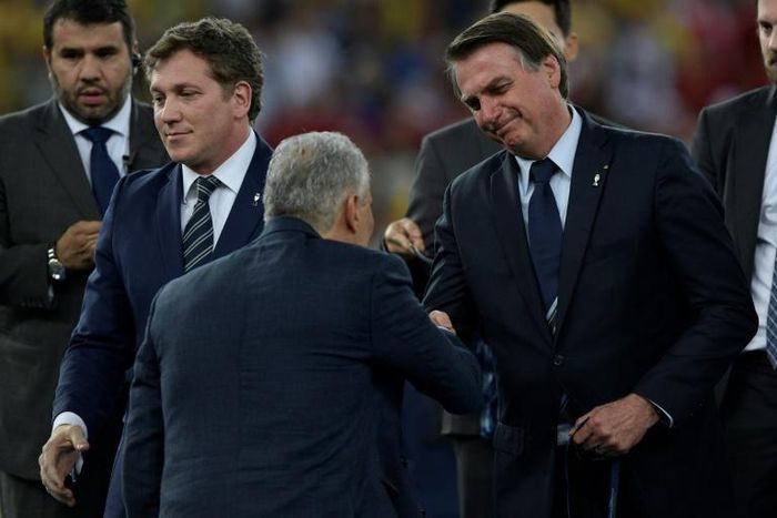 Brazil coach Tite (center) shakes hands with Brazilian President Jair Bolsonaro (right) after leading his team to Copa America glory