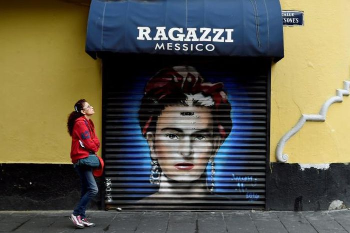 In this file picture taken on August 30, 2017 a woman walks past a mural of Mexican artist Frida Kahlo at Mesones street in Mexico City
