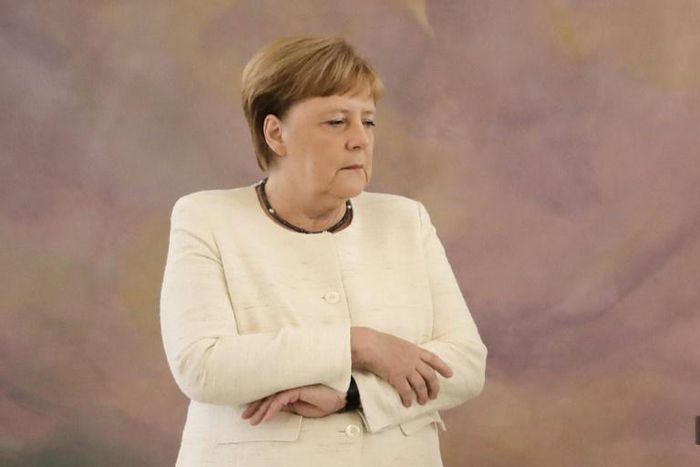 Merkel folded her arms visibly in a bid to stop the trembling. 