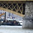 A picture taken on June 7, 2019 shows teams of experts and divers on boats on the Danube under the Margit Bridge during the operations to hoist the submerged boat following a boat accident in Budapest