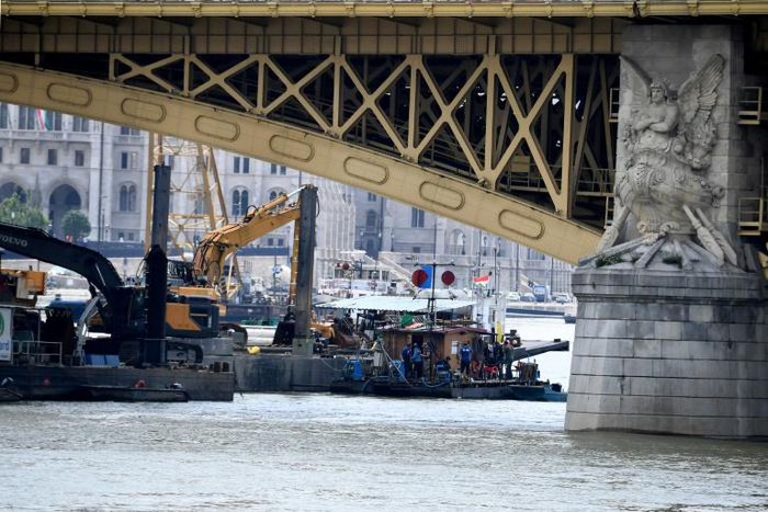 A picture taken on June 7, 2019 shows teams of experts and divers on boats on the Danube under the Margit Bridge during the operations to hoist the submerged boat following a boat accident in Budapest