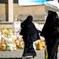 A Yemeni woman carries a sack of grain on her head while walking after receiving food aid provided by a local charity