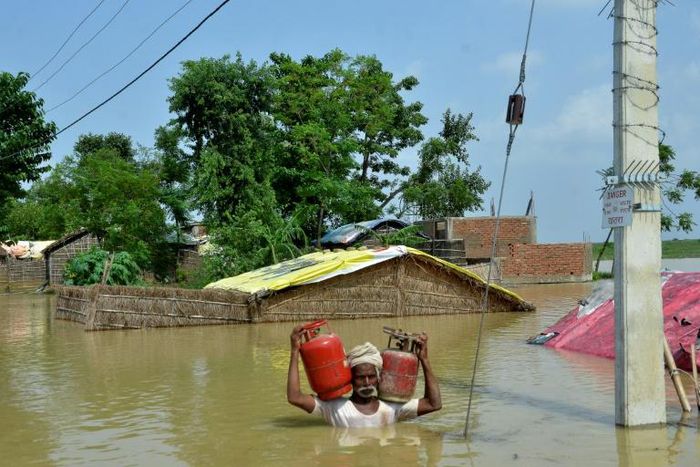 A resident of Muzaffarpur carries gas canisters from his flooded home following heavy monsoon rains in the Indian state of Bihar